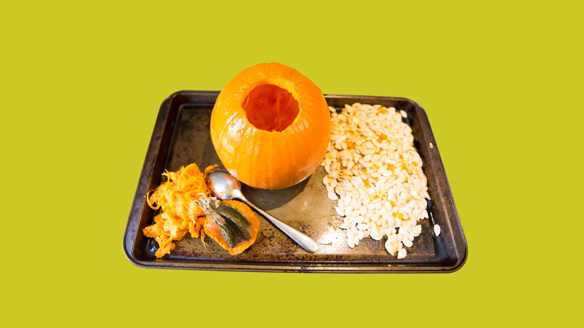 Cut a hole. Green background. Baking sheet with pumpkin with hole carved out at top.